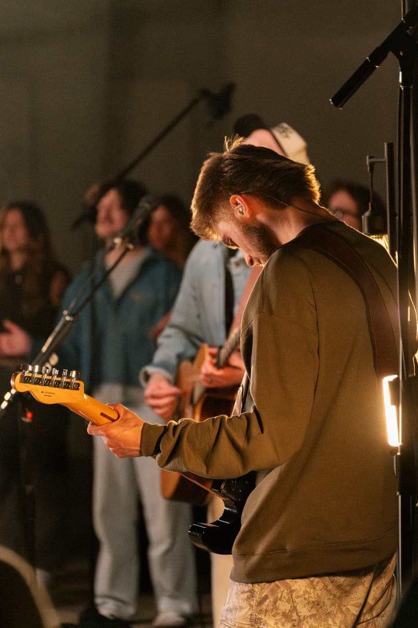Caden Chambers playing guitar under warm stage lighting